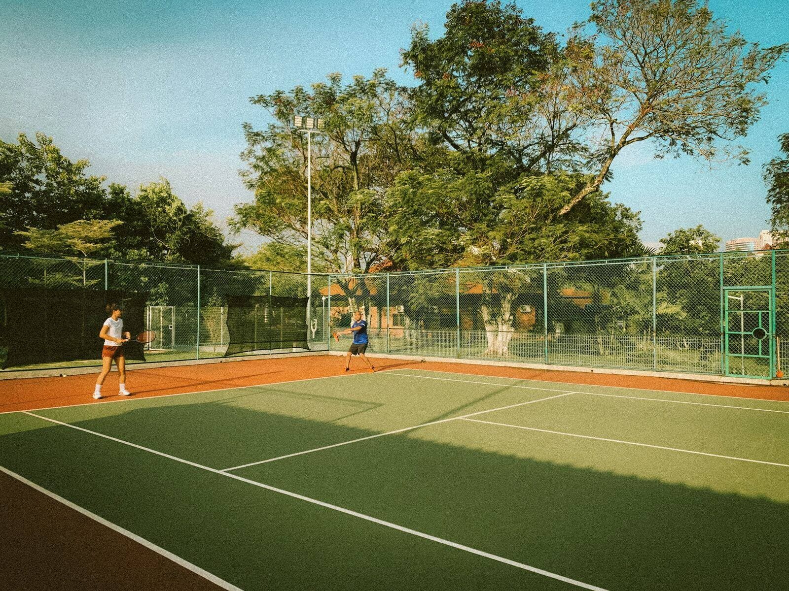 Two members playing tennis on an outdoor court