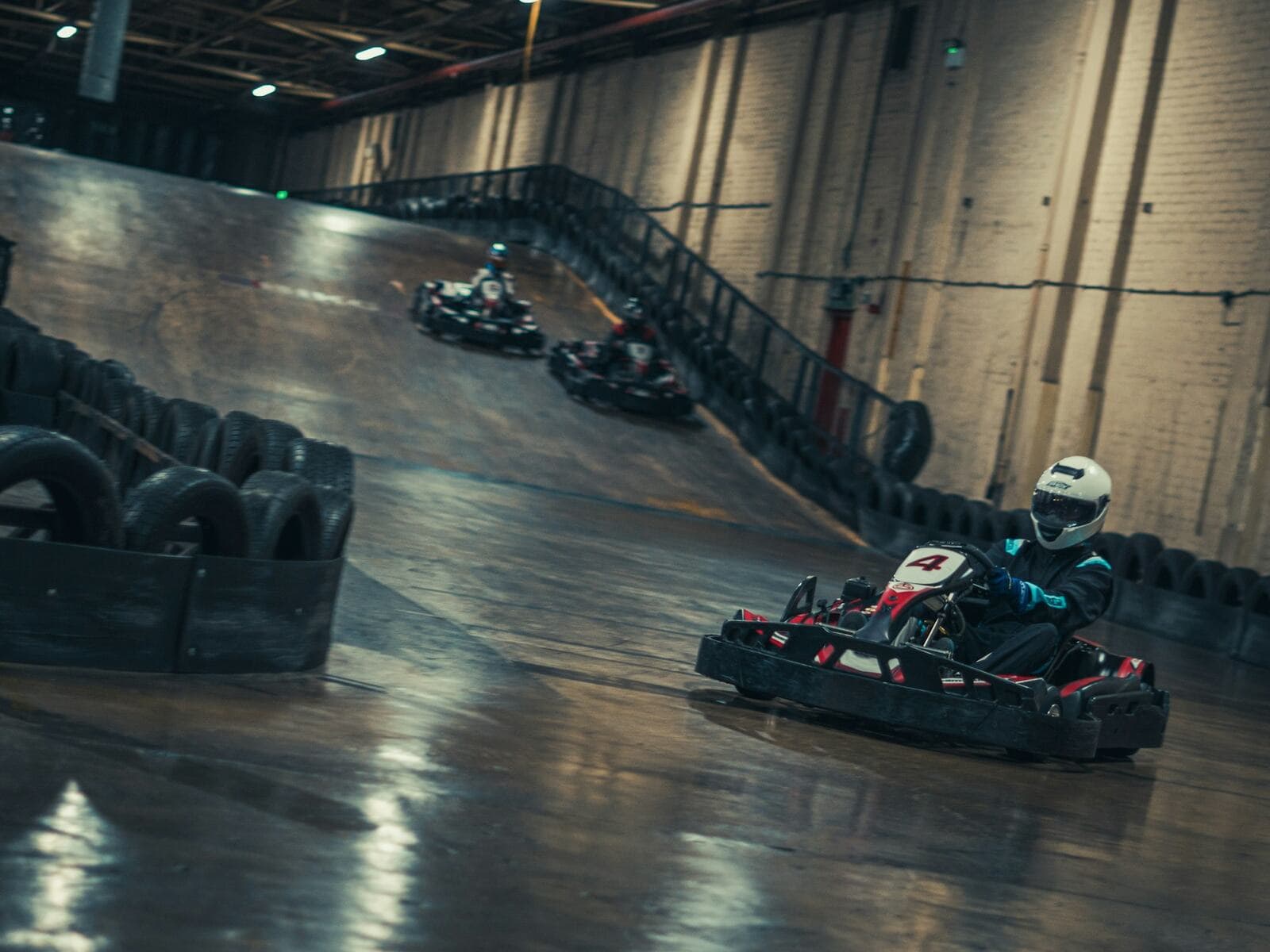 Drivers racing go karts around an indoor track